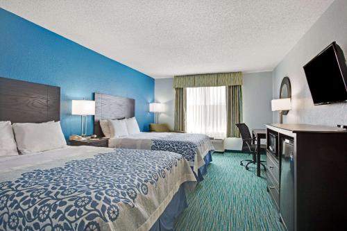 a hotel room with two beds and a flat screen tv at Days Inn by Wyndham Dallas Garland West in Garland