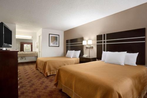 a hotel room with two beds and a flat screen tv at Travelodge by Wyndham Killeen/Fort Hood in Killeen
