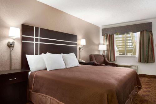 a hotel room with a large bed and a chair at Travelodge by Wyndham Killeen/Fort Hood in Killeen