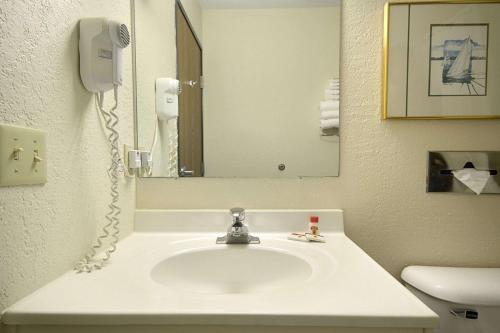 baño con lavabo con espejo y teléfono en Travelodge by Wyndham Hudsonville, en Hudsonville