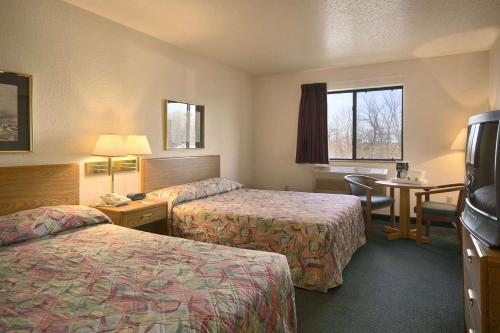 Habitación de hotel con 2 camas y mesa en Travelodge by Wyndham Hudsonville, en Hudsonville