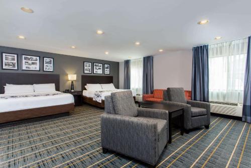 a hotel room with two beds and two chairs at Baymont by Wyndham Lancaster in Lancaster