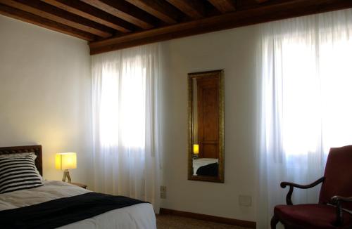 a bedroom with a bed and a mirror and curtains at Appartamenti San Luca in Venice