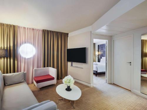 uma sala de estar com um sofá e uma televisão em Mercure Paris La Défense em Courbevoie