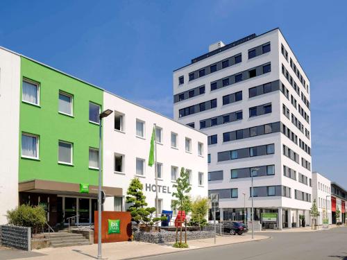 a green and white building next to a street at ibis Styles Arnsberg - Neheim in Arnsberg