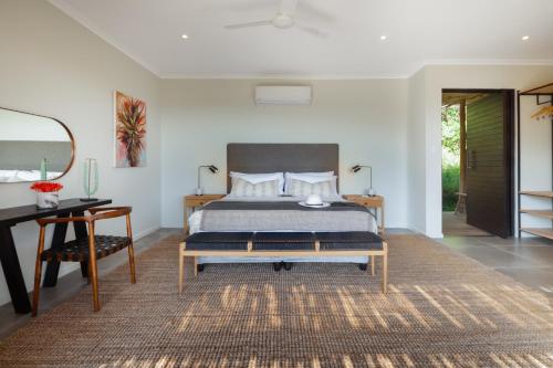 a bedroom with a bed and a table and a mirror at Sungulwane Private Game Lodge in Hluhluwe