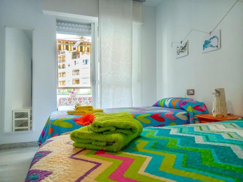 - une chambre colorée avec 2 lits et des serviettes dans l'établissement Apartamento Hibisco , Primera Línea de Playa, à Almuñécar