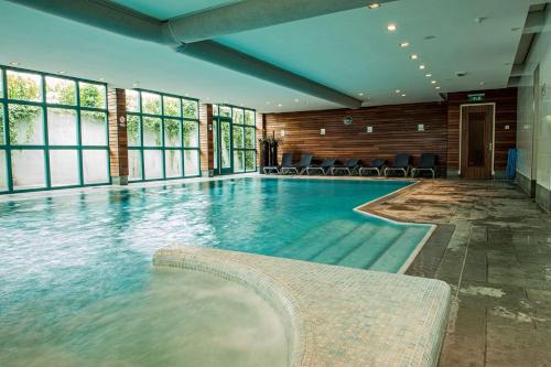 - une piscine dans un hôtel avec des chaises et des fenêtres dans l'établissement Best Western Hotel Nobis Eindhoven-Venlo A67, à Asten