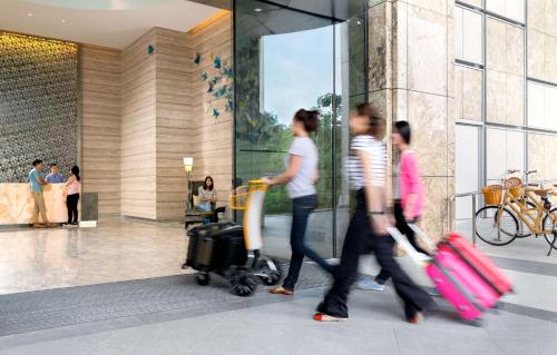 a group of people walking in a lobby with luggage at JEN Singapore Orchardgateway by Shangri-La in Singapore