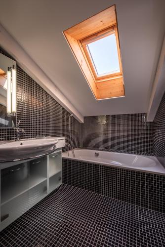a bathroom with a sink and a tub and a window at Chalet Schneehoren Penthouse in Wengen