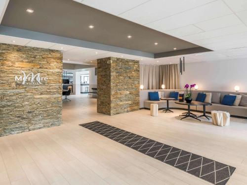 a lobby of a hotel with a stone wall at Mercure Hotel & Spa Bastia Biguglia in Biguglia