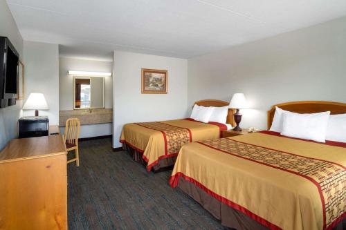 a hotel room with two beds and a flat screen tv at Pigeon Forge Parkway Inn in Pigeon Forge