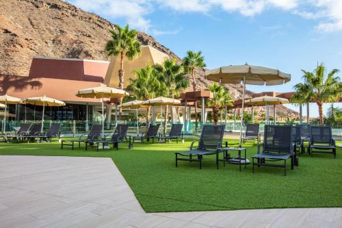 eine Gruppe von Stühlen und Tischen mit Sonnenschirmen in der Unterkunft Radisson Blu Resort & Spa, Gran Canaria Mogan in Puerto de Mogán