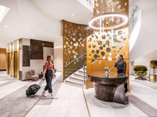 two women walking through a hotel lobby with a suitcase at Novotel Leicester in Leicester