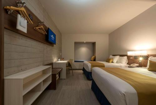 グアダラハラにあるMicrotel Inn & Suites by Wyndham Guadalajara Surのベッド2台と机があるホテルの部屋