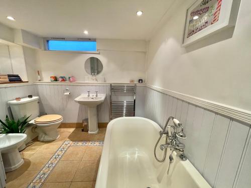 a bathroom with a tub and a toilet and a sink at The Writer's Cottage in Deal