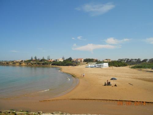 a beach with people sitting under an umbrella at Vista Mare tra i luoghi di Montalbano in Punta Secca