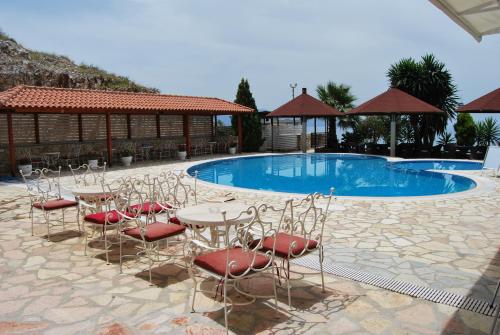 uma piscina com mesas e cadeiras em frente a um edifício em Hotel Panorama Sarande em Sarandë