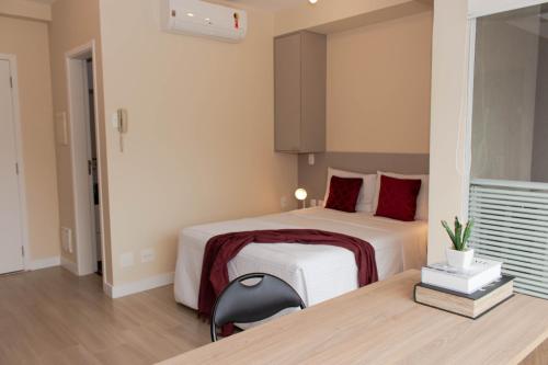 a bedroom with a bed with red pillows and a desk at 360 Perdizes in Sao Paulo