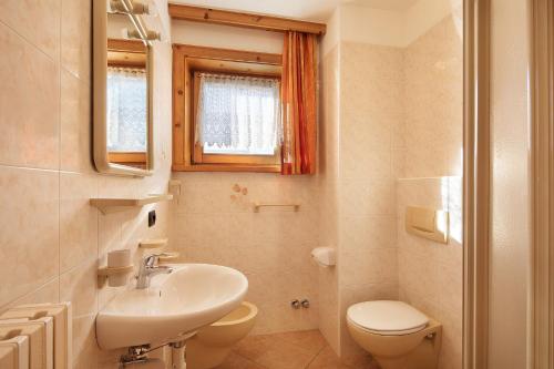 ein Badezimmer mit einem Waschbecken, einem WC und einem Spiegel in der Unterkunft Baita sulle Alpi in Livigno