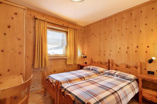 ein Schlafzimmer mit einem Bett in einem Zimmer mit Holzwänden in der Unterkunft Baita sulle Alpi in Livigno