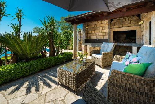 an outdoor patio with wicker chairs and a fireplace at Villa Mia in Trsteno
