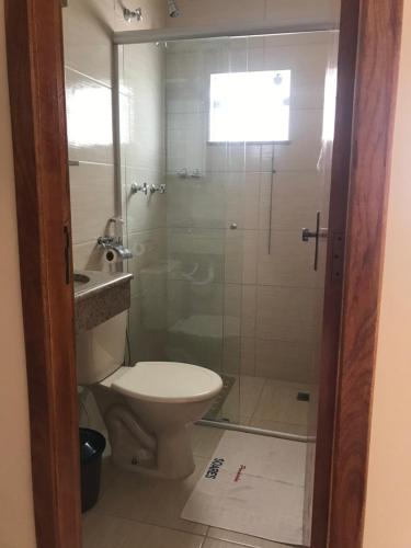 a bathroom with a toilet and a glass shower at Pousada Soares in Aparecida