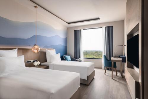 a hotel room with two beds and a desk at Novotel Chandigarh Tribune Chowk in Chandīgarh