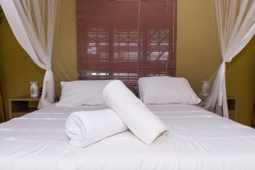 a bedroom with two beds with white sheets and a window at Casa da Noleen in Matola