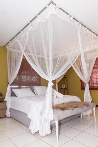 a bedroom with a canopy bed with white drapes at Casa da Noleen in Matola