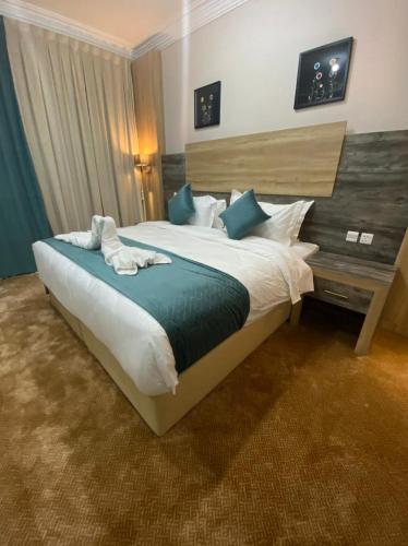 a bedroom with a large bed with blue pillows at الاطلاله للشقق المخدومة in Khamis Mushayt