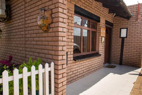 a brick house with a white fence next to it at Casa da Noleen in Matola
