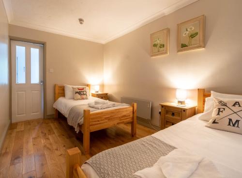 a bedroom with two beds and two tables with lamps at The Farmhouse at Fincham in Fincham