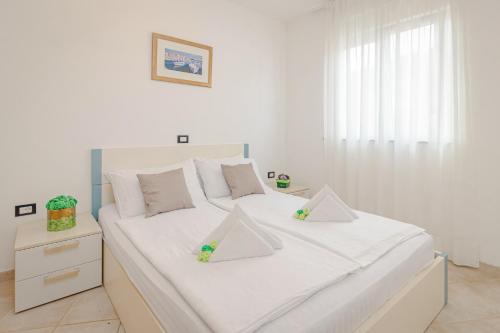 a white bed with white sheets and pillows on it at Residence Kamenjak in Premantura