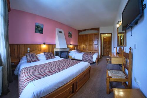 a hotel room with two beds and a flat screen tv at Hotel Victoria in Metsovo