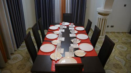 een lange tafel met witte borden en rode servetten bij Veke Executive Lodge & Event Center in Cape Coast