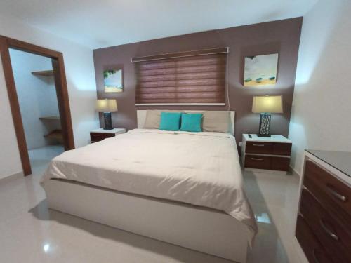 a bedroom with a large bed with blue pillows at Torre Real IV L3 Santiago DR con cocinero para desayuno in Santiago de los Caballeros