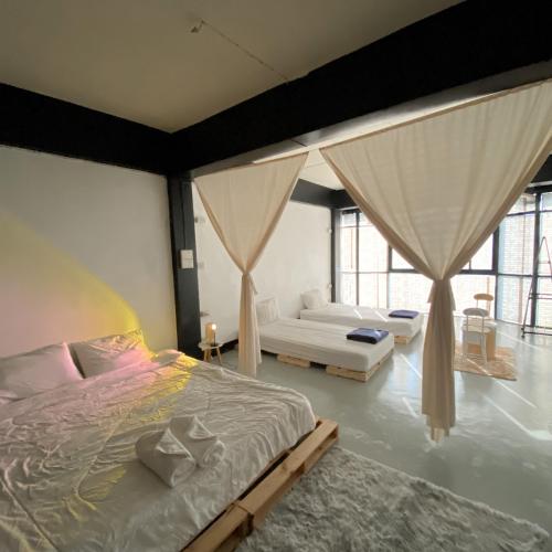 a bedroom with a bed and a couch and windows at FrenTé Chiang Mai in Chiang Mai