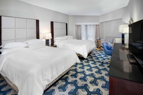 a hotel room with two beds and a flat screen tv at Sheraton Eatontown Hotel in Eatontown