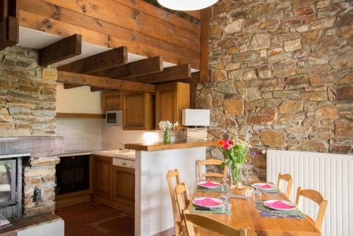 - une cuisine avec une table et un mur en pierre dans l'établissement Village de gîtes de Barre-des-Cévennes, à Barre-des-Cévennes