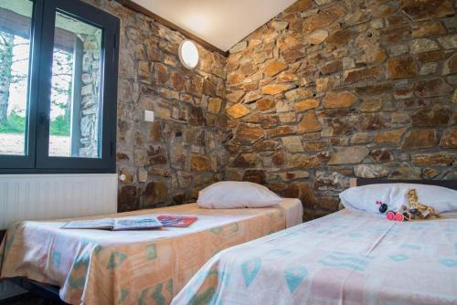 twee bedden in een kamer met een stenen muur bij Village de gîtes de Barre-des-Cévennes in Barre-des-Cévennes