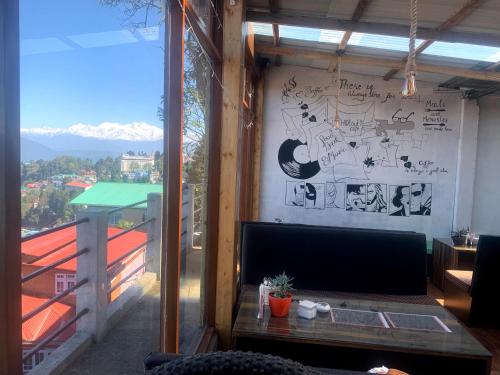 a living room with a tv and a large window at Hideout Homestay in Darjeeling