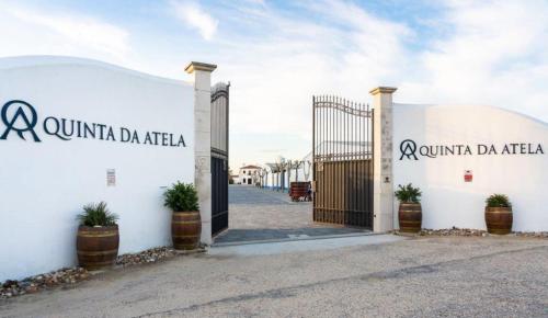 a white building with a gate and potted plants at Quinta da Atela in Alpiarça