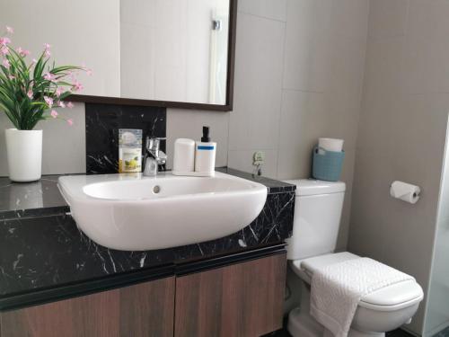 a bathroom with a white sink and a toilet at Landmark Million Dollar King Suite #Netflix#500mbps Wifi#Atari in Tanjong Tokong