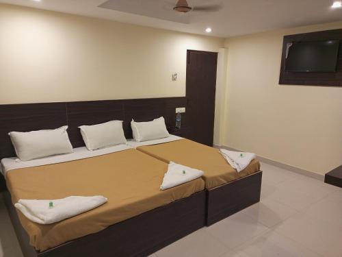 哥印拜陀的住宿－Purple Inn，一间卧室配有一张带白色枕头的床和电视。