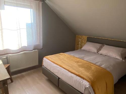 "Chez Mima" - à deux pas de Durbuy! في دربي: غرفة نوم عليها سرير مع بطانية صفراء