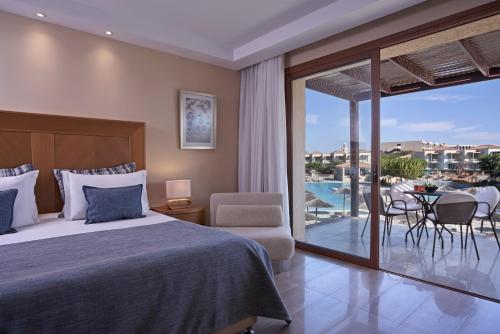 a bedroom with a bed and a balcony with a table and chairs at Atlantica Aegean Park in Kolimbia