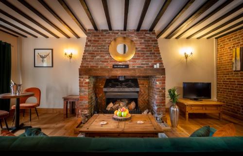 a living room with a brick fireplace with a table at The Farmhouse at Fincham in Fincham