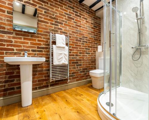 a bathroom with a sink and a brick wall at The Farmhouse at Fincham in Fincham