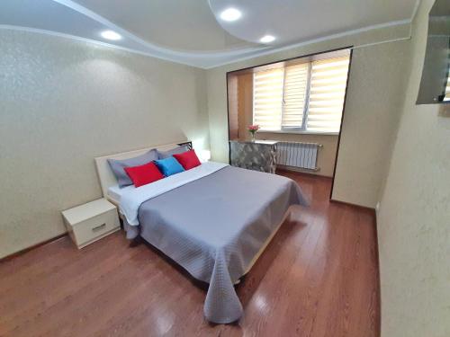 een slaapkamer met een groot bed met rode en blauwe kussens bij Уютная квартира класса ЛЮКС в городе Тараз in Taraz